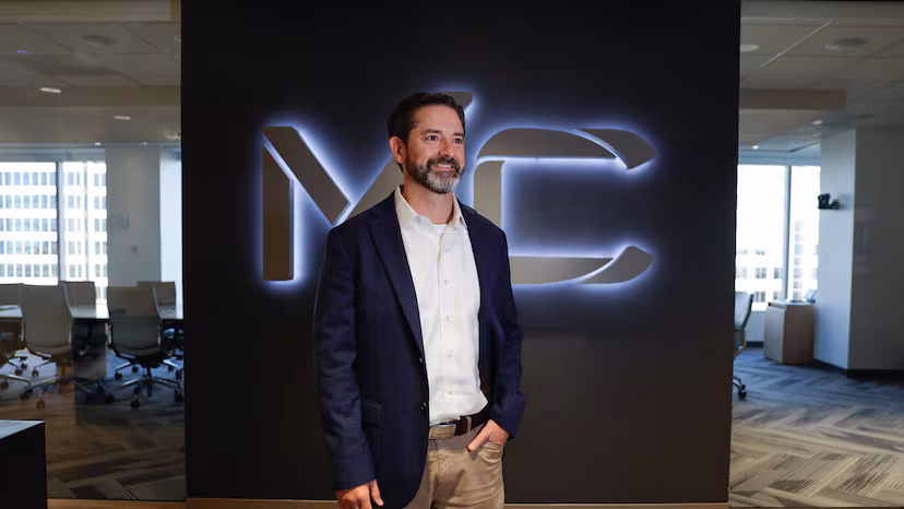 Moore Colson Managing Partner Andy Starnes in the Moore Colson office in front of a large conference room and a backlit "MC" sign.