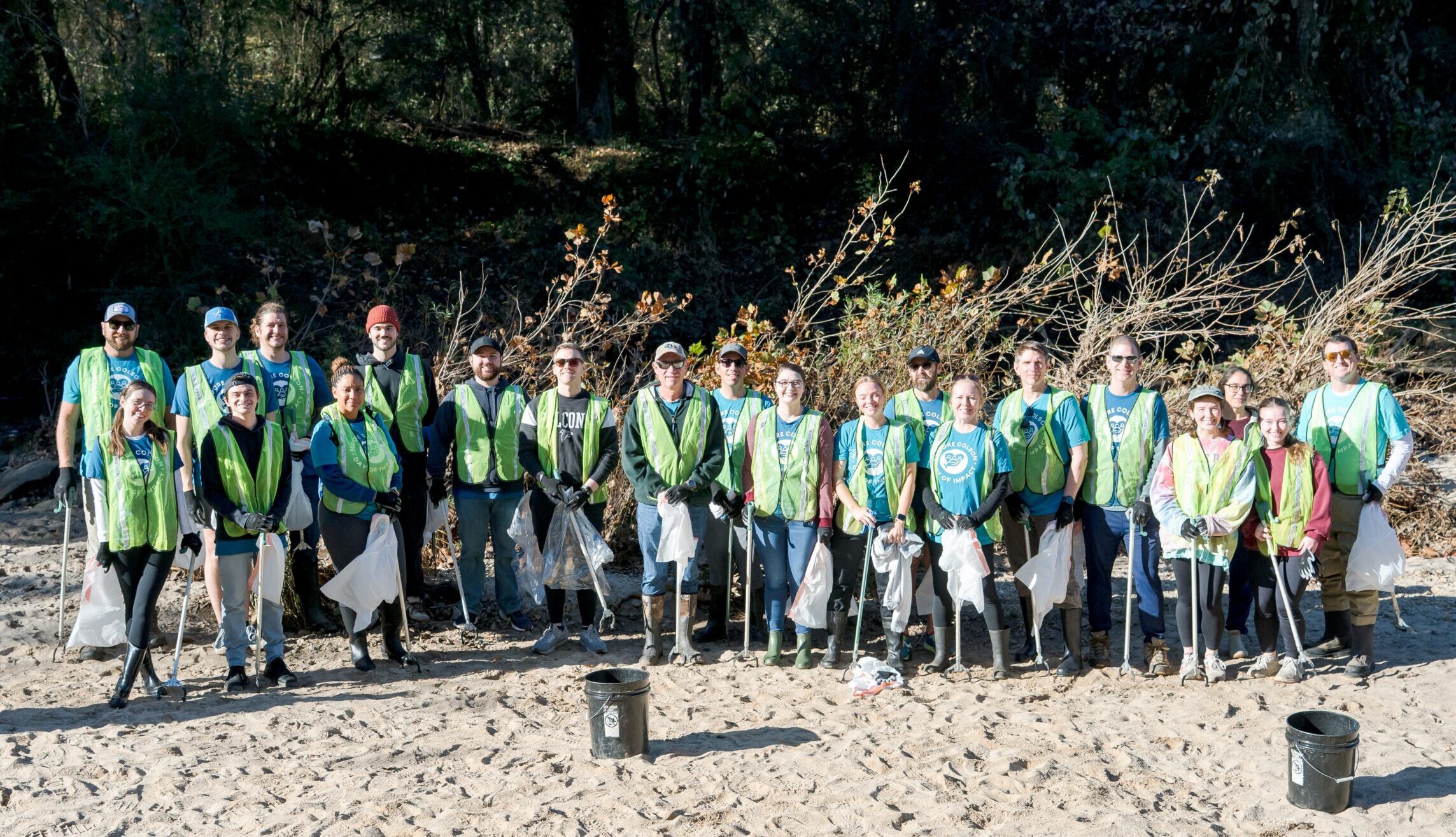 Moore Colson employees standing in a line smiling and holding tools at a Day of Impact Community Service event