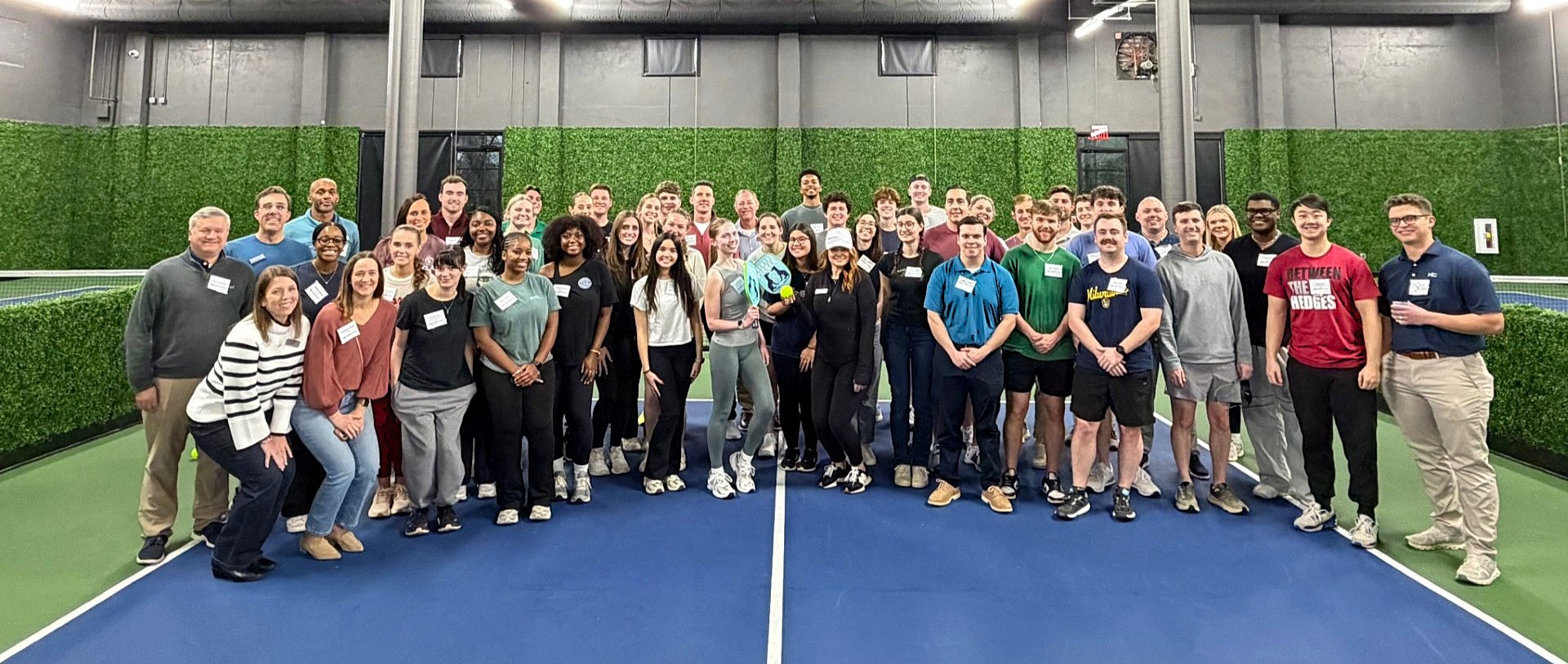 Group of Moore Colson employees and interns standing and smiling on a court at the intern kickoff event.