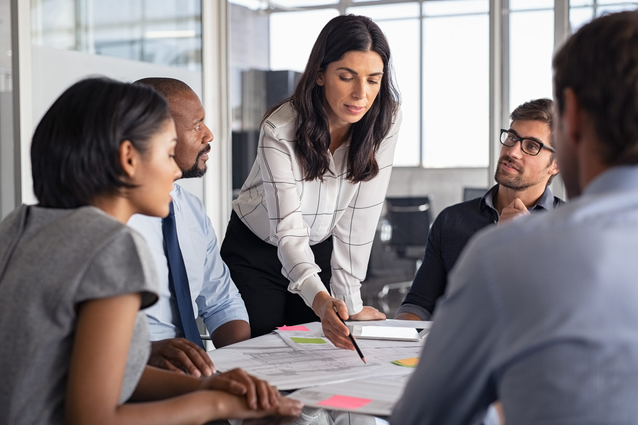 Business valuation advisor pointing to financial documents while colleagues review data nearby.