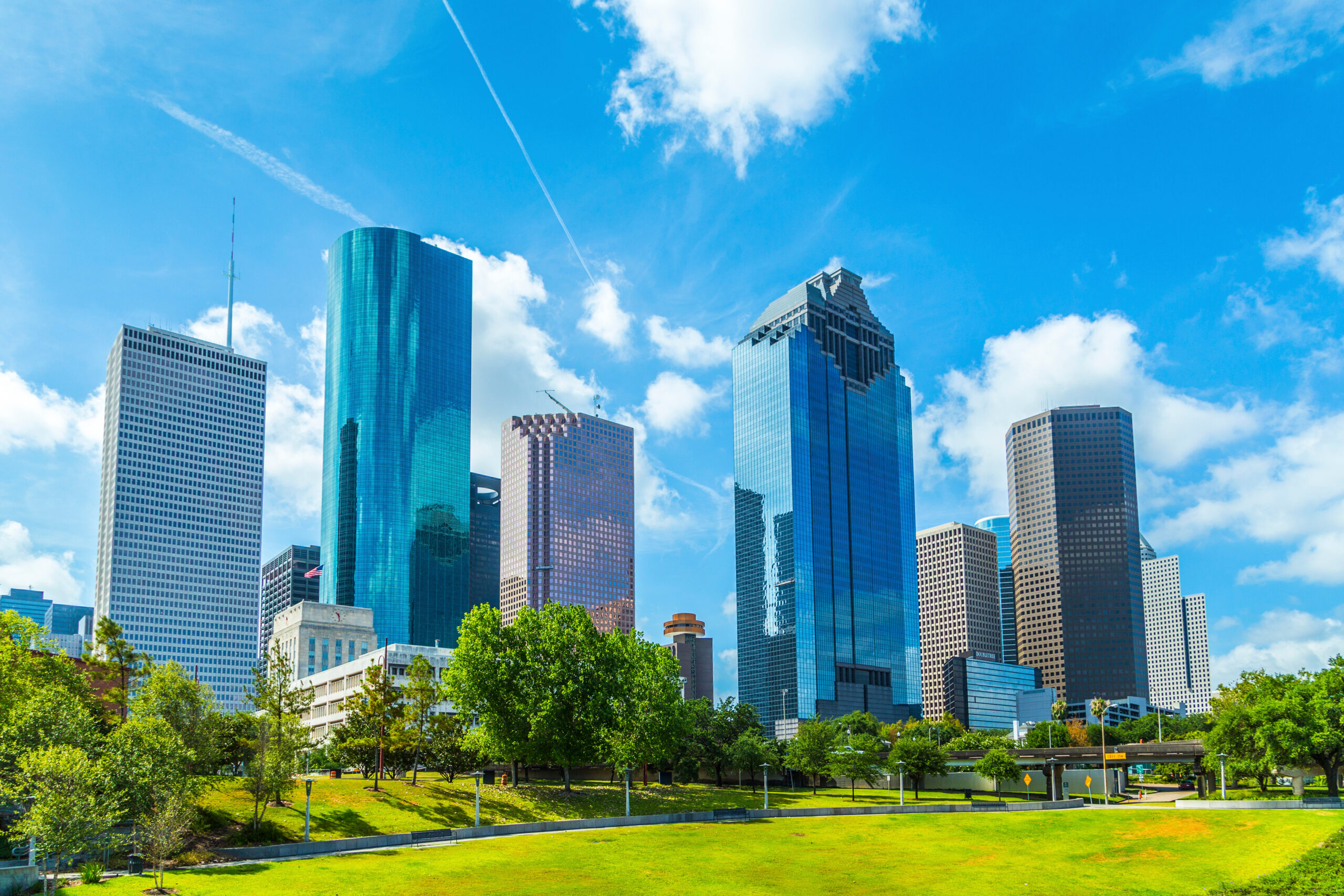 Downtown Houston skyline with skyscrapers and green park, home to Moore Colson's Houston business valuation clients.