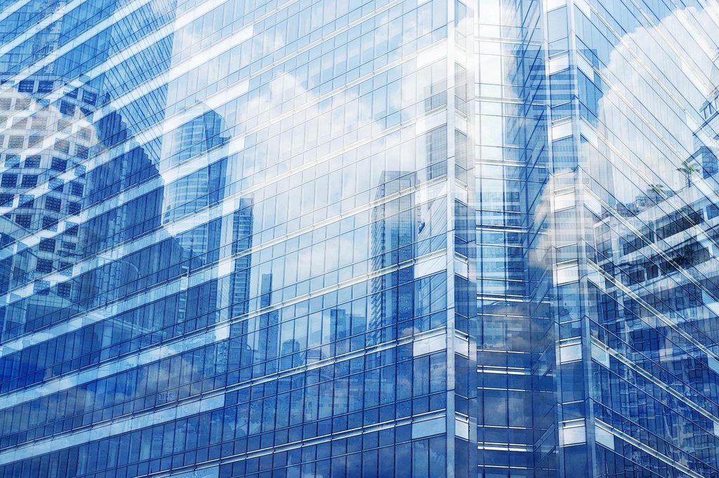 Close up of an office building with reflections of other buildings in the windows